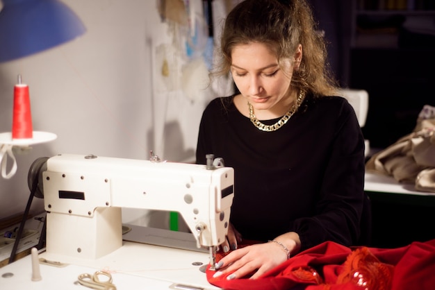 Modista trabajando en la máquina de coser. Confección a medida de una prenda. Hobby coser como un concepto de pequeña empresa.