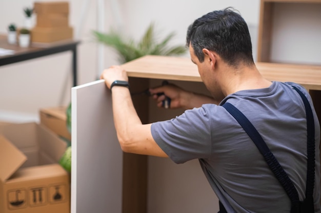 Möbelmontage im Haus eines erfahrenen Kunden, der weiße Tür an einem Holzschrank anbringt