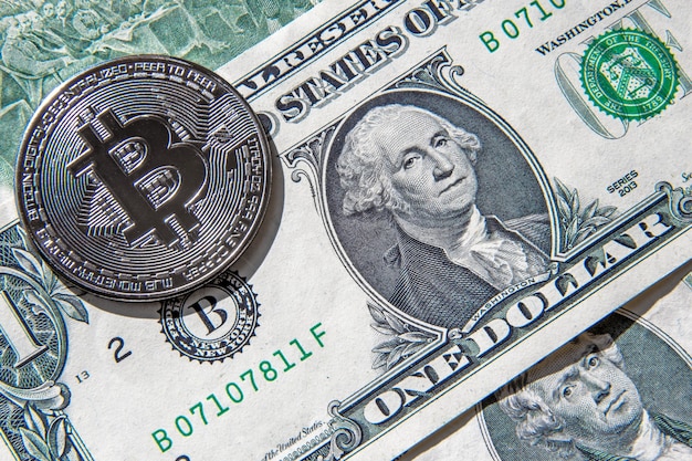 Moeda bitcoin dourada acima das notas de um e duas notas de dólar americano