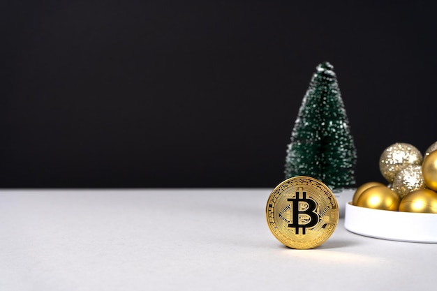 Moeda de ouro com sinal de bitcoin com árvore de Natal e bolas de Natal em fundo cinza e preto. Mineração de criptomoeda. presente de Natal