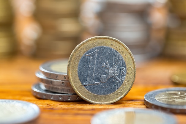 Moeda de um euro em pé na mesa de madeira de perto.