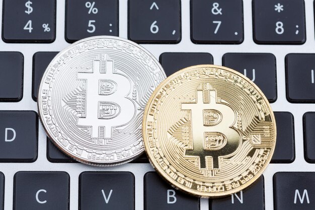 Moeda digital prata física e moedas de bitcoin douradas no teclado de computador preto