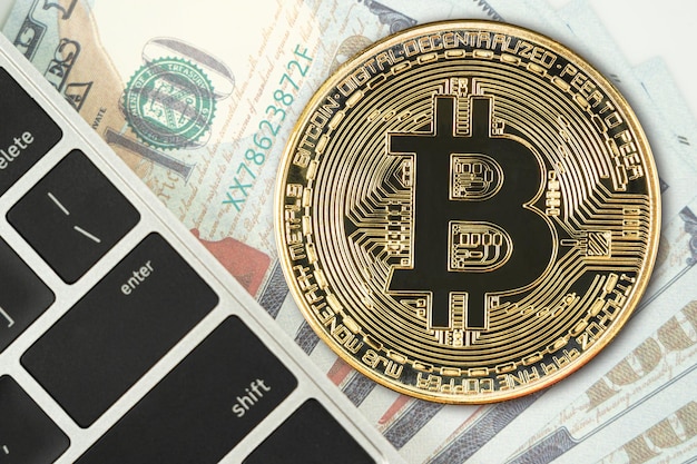 Moeda dourada de bitcoins e cédulas dos eua com teclado de computador