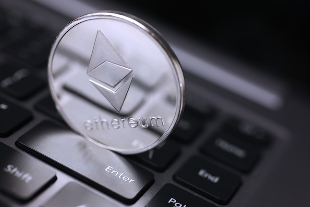 Moeda ethereum de prata deitada no laptop