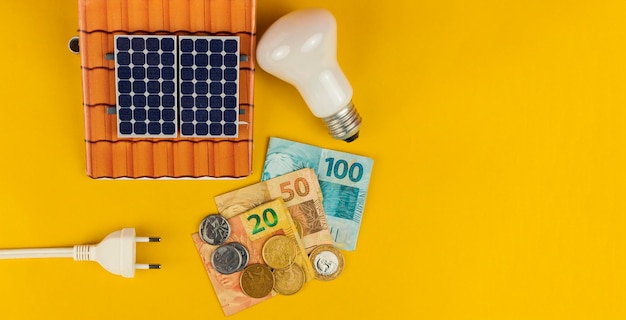 Foto moedas de notas conectam fio e lâmpadas isoladas em fundo amarelo conceito de energia brasileiro de inflação elétrica