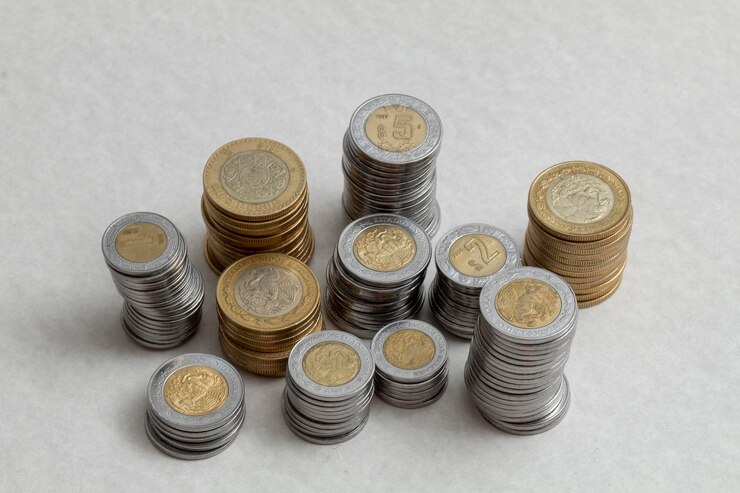 Moedas de pesos mexicanos empilhadas por denominações em uma mesa