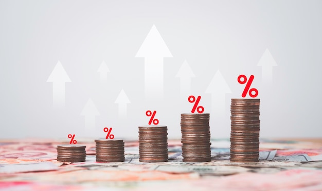 Moedas empilhadas com seta branca para cima e porcentagem em notas internacionais para aumentar a taxa de juros financeiros e o conceito de inflação