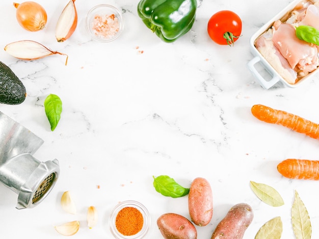 Moedor de carne retrô manual com legumes em uma mesa de mármore com espaço de cópia