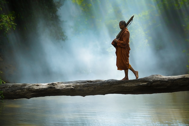 Mönch Wandern Überqueren Sie den Fluss im Wald, Thailand,