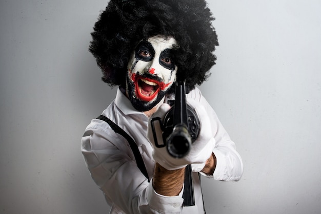 Mörderclown, der ein Gewehr auf strukturiertem Hintergrund hält