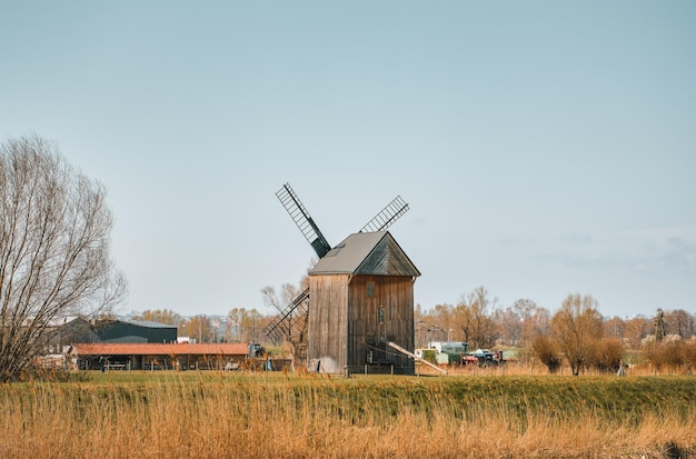 Moinho de vento de madeira fica na costa de um canal Paisagem de primavera de uma área rural na Polônia
