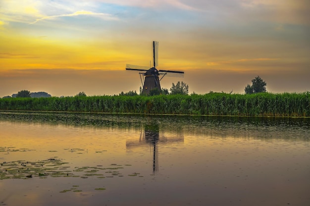 Moinho de vento holandês velho ao pôr do sol em Kinderdijk Holanda