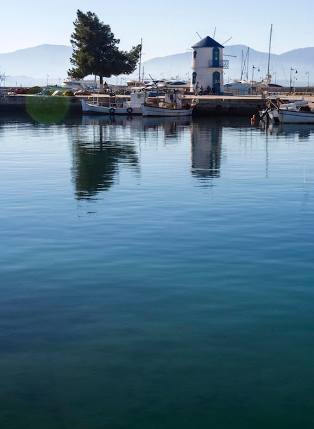 Moinho e barcos de pesca no mar Egeu calmo em um dia ensolarado na ilha de Evia Grécia