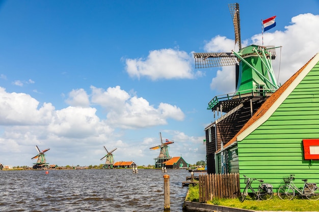 Moinhos de vento coloridos com bandeiras holandesas no rio Zaan Zaanse Schans Zaandam, Holanda