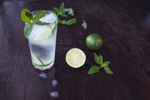 Foto mojito cocktail em um fundo escuro de madeira. suco de limão fresco com hortelã e gelo. bebida refrescante.