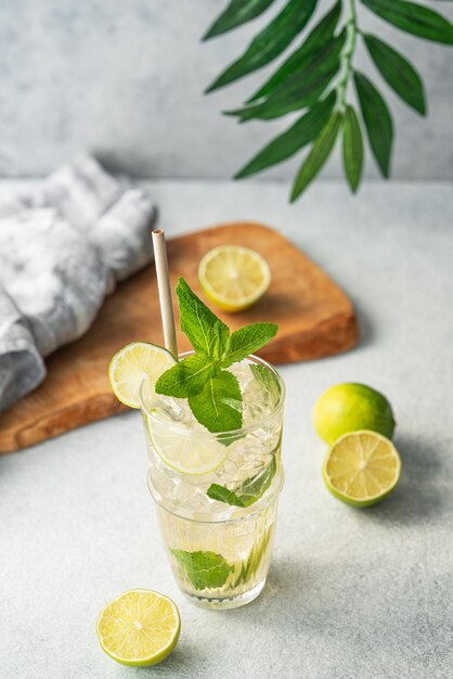 Mojito-Cocktail in einem hohen Glas mit Limettenminze und Eis auf einem hellen Hintergrund Trendiges Sommer-Erfrischungsgetränk-Konzept