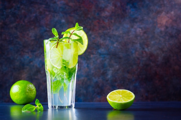 Mojito cocktail con lima y menta sobre fondo oscuro