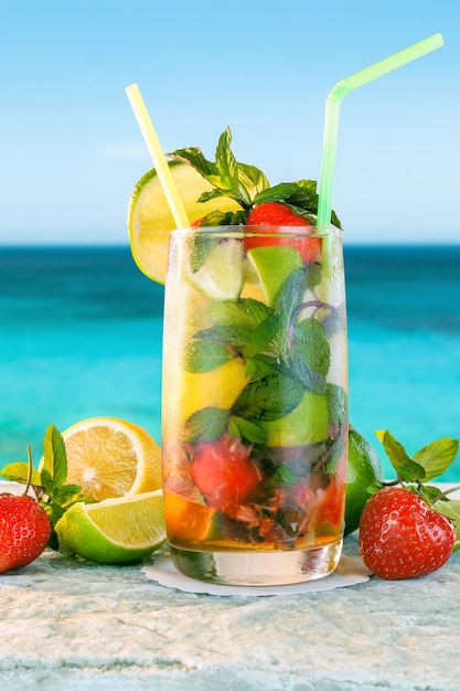 Mojito-CocktailWeißer Rum-Cocktail mit frischen ZutatenKaltes Eisgetränk auf verschwommenem Strandhintergrund