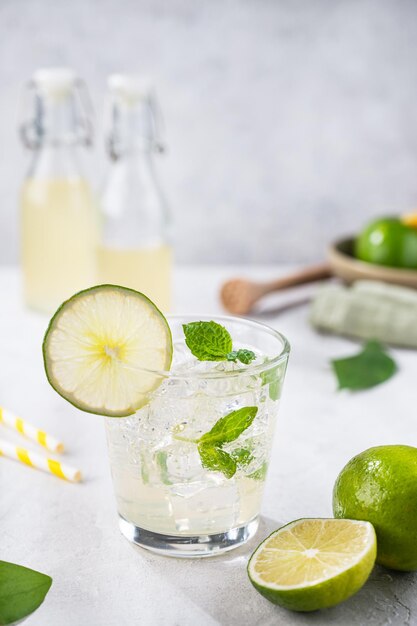 Mojito de cóctel frío fresco con menta y hielo Concepto de verano bebida cítrica con limas sobre fondo gris Vista frontal