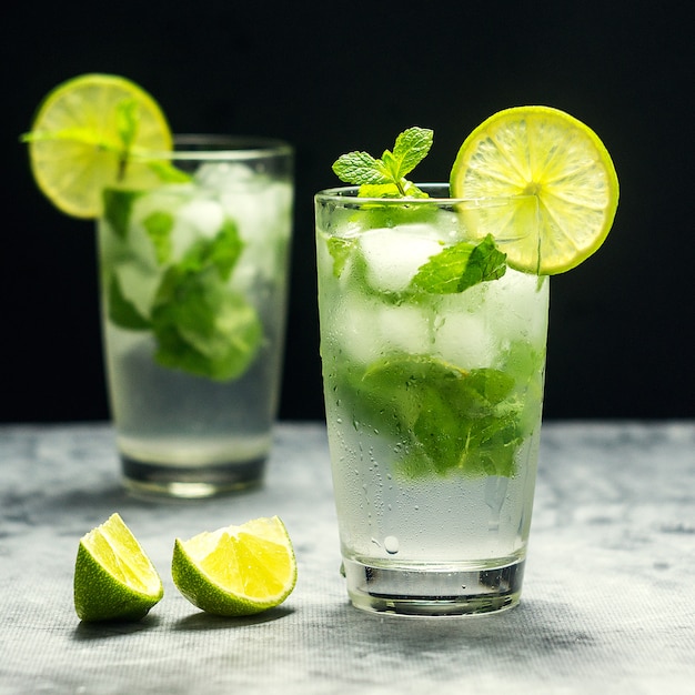 Mojito cóctel con limón y menta en vidrio sobre una piedra gris. Cuadrado