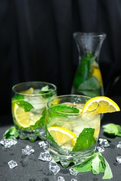 Mojito erfrischendes Cocktail-Alkoholgetränk Limonade mit Zitrone und Minzblättern auf dunklem Hintergrund Eiswürfel Erfrischende Detox-Getränke im Sommer Sauberes Essen gesundes Lifestyle-Konzept