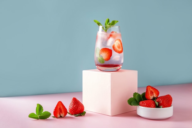 Mojito de fresa sobre fondo azul y podio rosa. Bebida refrescante de verano con espacio de copia