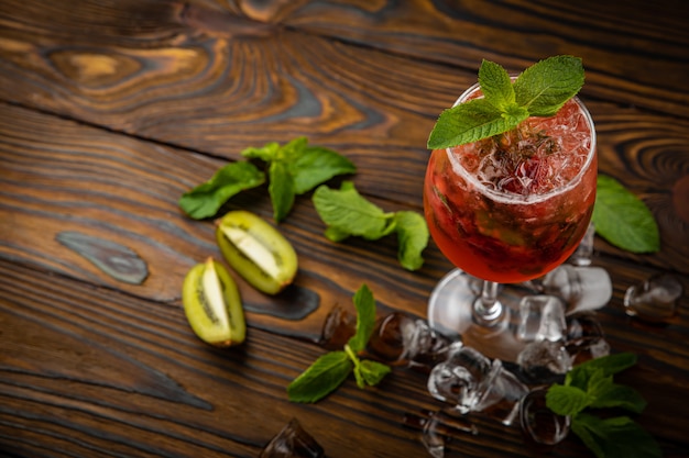 Mojito con fresas, frambuesas y menta en una mesa de madera marrón