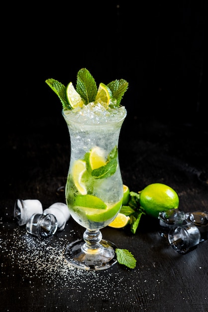 Mojito fresco con hielo y limón sobre fondo negro