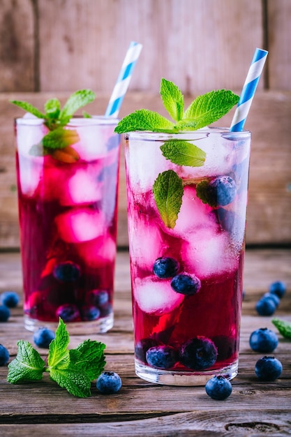 Mojito de hielo de arándanos con menta en vasos sobre fondo de madera