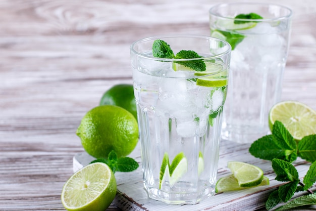 Mojito de limonada de verano refrescante frío en un vaso sobre fondo blanco de madera