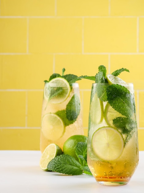 Mojito ou bebida de rum longo mojito virgem com açúcar de cana de suco de limão de menta fresca e refrigerante em fundo amarelo