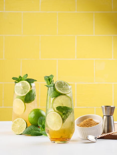 Mojito ou bebida de rum longo mojito virgem com açúcar de cana de suco de limão de menta fresca e refrigerante em fundo amarelo