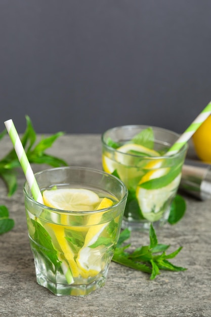 Mojito-Sommer-Erfrischungscocktail mit Eis und Minze Mojito-Cocktail mit Limette, Zitrone und Minze in einem hohen Glas mit einem Stock