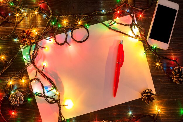 Foto mokcup de año nuevo y navidad. cuaderno con luces de navidad sobre fondo de madera, espacio para el texto, copyspace. desde arriba. concepto de planificación de vacaciones de invierno. estilo plano.