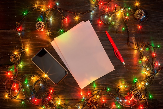 Mokcup de ano novo e natal. caderno com luzes de natal em fundo de madeira, espaço para seu texto, copyspace. de cima. conceito de planejamento de férias de inverno. estilo liso leigo.