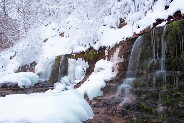 Molas quentes e cachoeira contra o pano de fundo de neve fresca e gelo no inverno