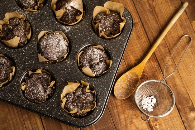 Molde para hornear con un sabroso muffins de chocolate en la mesa de madera