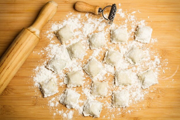 Molde de ravioli de ravioli casero y un rodillo sobre una mesa de madera