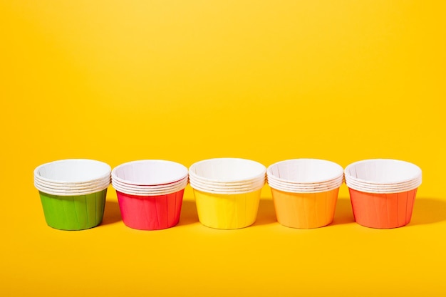 Moldes de papel multicolorido para muffins e cupcakes em um fundo amarelo