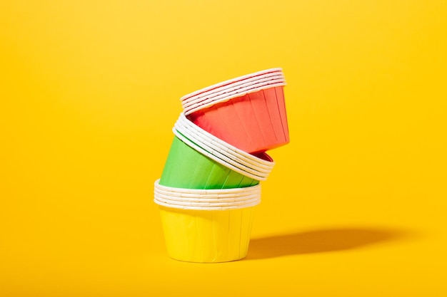 Moldes de papel multicolorido para muffins e cupcakes em um fundo amarelo