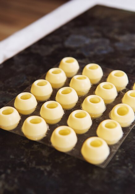 Moldes de repostería esféricos vacíos de chocolate blanco sobre una superficie de mármol. De cerca