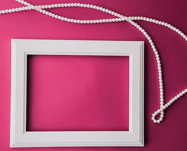 Moldura de arte horizontal branca e joias de pérola em fundo rosa como impressão de arte de design flatlay ou álbum de fotos