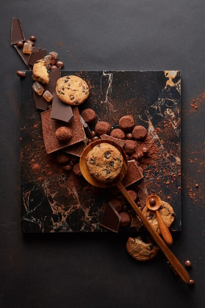 Moldura de biscoitos caseiros com chocolates e doces na bandeja de mármore e um fundo preto