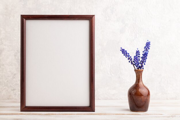 moldura de madeira com flores de jacinto muscari em vaso de cerâmica sobre fundo cinza de concreto. copie o espaço