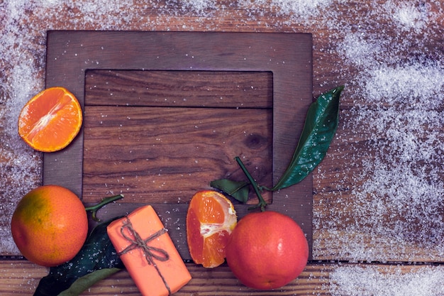 Moldura de madeira com tangerinas e presente