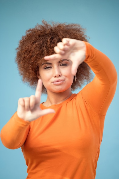 Moldura de mãos e retrato de mulher negra em fundo azul para foto de perfil Face feminina e enquadramento de dedo para selfie em perspectiva e visão de ideia de foco estético e fotografia em estúdio