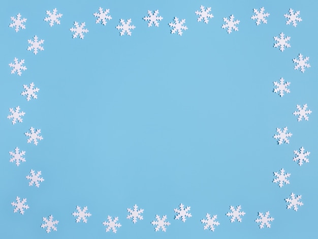 Moldura de natal com flocos de neve brancos sobre fundo azul pastel. espaço para texto.