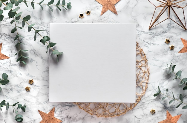 Moldura de natal com galhos de eucalipto frescos e decorações geométricas - hexágonos, formas de arame. vista superior na moda em fundo de mármore branco. cópia-espaço em tela branca.