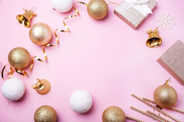 Foto moldura de natal com presentes de bolas de ouro e sinos em um fundo rosa estilo liso leigo