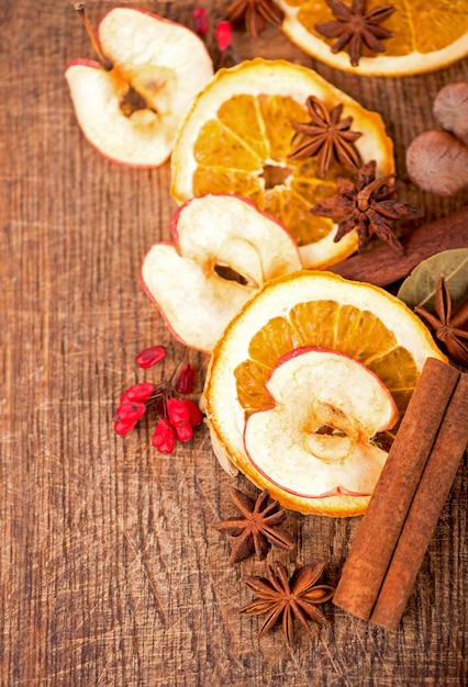 Moldura de natal especiarias e fatias de laranja secas sobre uma mesa de madeira